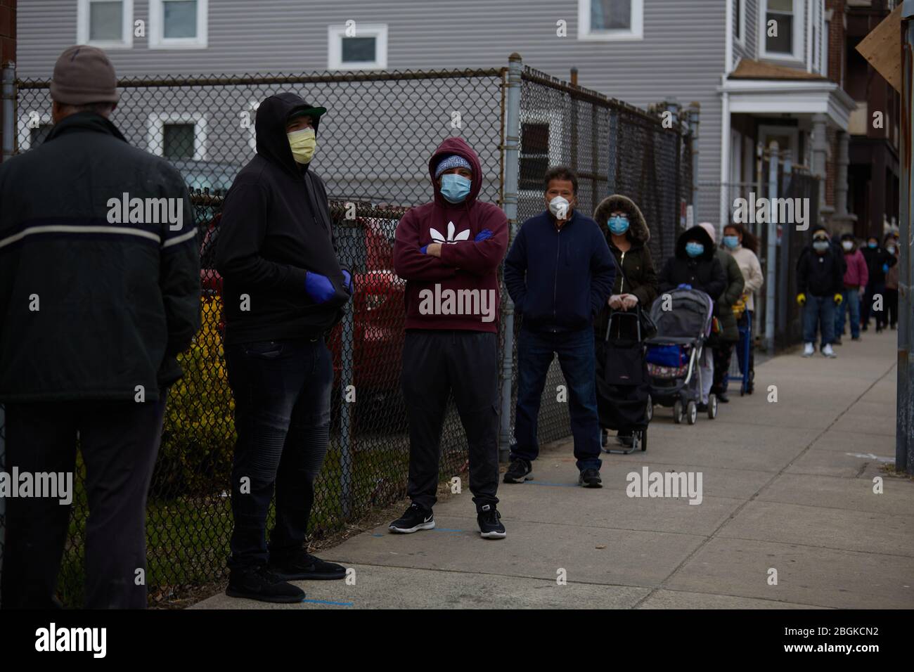 Chelsea, Massachusetts, Stati Uniti. 21 Apr 2020. I residenti attendono in fila per raccogliere le scatole di cibo e i pasti caldi. Il COVID-19, Corona Virus, situazione a Chelsea, Massachusetts è un punto caldo importante. Chelsea è la città più colpita dello stato. Il Chelsea è una popolazione pesante immigrata latinoamericana con il 80% della popolazione che è lavoratori essenziali, come i drogheria. Con i lavori persi la gente ha un momento duro potere ottenere il cibo. L'Esercito della salvezza dà fuori le scatole del cibo e i pasti caldi giornalmente. Le linee si strecth per i blocchi della città per ottenere le scatole del cibo. Credito: Allison Dinner/ZUMA Wire/Alamy Live News Foto Stock