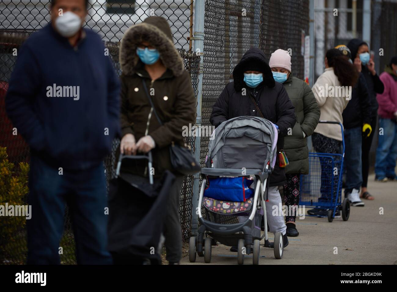 Chelsea, Massachusetts, Stati Uniti. 21 Apr 2020. I residenti attendono in fila per raccogliere le scatole di cibo e i pasti caldi. Il COVID-19, Corona Virus, situazione a Chelsea, Massachusetts è un punto caldo importante. Chelsea è la città più colpita dello stato. Il Chelsea è una popolazione pesante immigrata latinoamericana con il 80% della popolazione che è lavoratori essenziali, come i drogheria. Con i lavori persi la gente ha un momento duro potere ottenere il cibo. L'Esercito della salvezza dà fuori le scatole del cibo e i pasti caldi giornalmente. Le linee si strecth per i blocchi della città per ottenere le scatole del cibo. Credito: Allison Dinner/ZUMA Wire/Alamy Live News Foto Stock