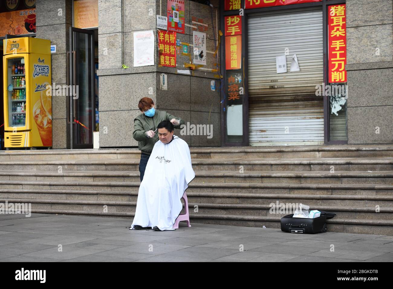 Un barbiere fa un taglio di capelli per una persona sulla strada nel distretto di Yubei nel Chongqing della Cina del sud-ovest, 4 marzo 2020. Foto Stock