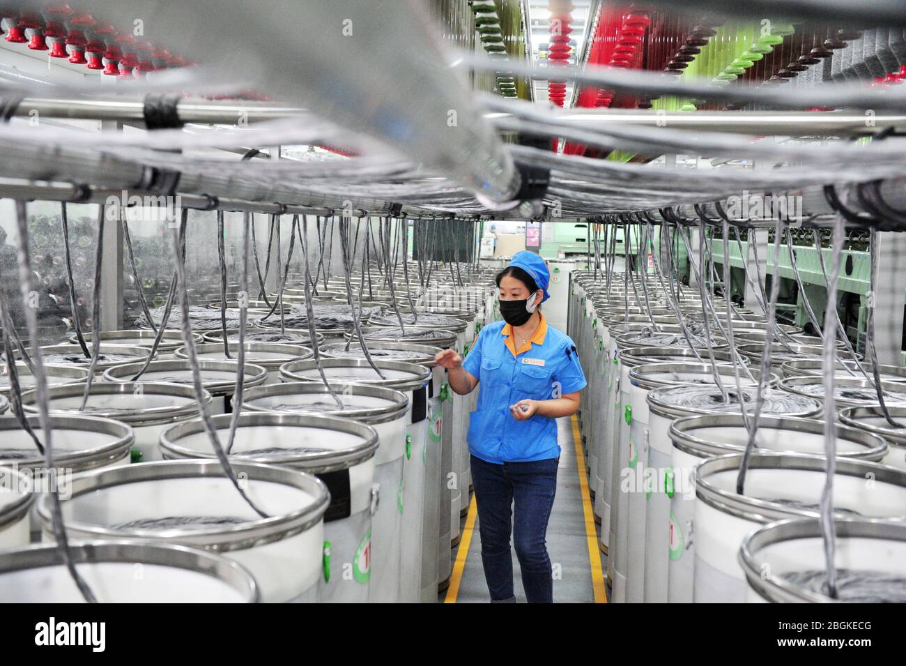 Il personale del mulino a filatura Tianhong, una fabbrica locale che ha ottenuto la ripresa completa della produzione, lavora lungo la linea di produzione automatizzata, nella contea di Suining, Xuzh Foto Stock