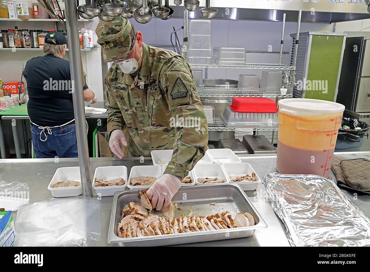 Guardia nazionale dell'esercito dell'Alaska Sgt. David Osmanson, assegnato al battaglione di ricattaggio e conservazione AKARNG, prepara piatti di tacchino affettati per pranzi caldi preconfezionati in cucina al Bean's Cafe di Anchorage, 8 aprile 2020. "Non potevamo fare quello che stiamo facendo senza l'aiuto di questi soldati", ha affermato Scott Lingle, direttore del servizio alimentare di Bean's Cafe. "Apprezziamo il lavoro, l'atteggiamento e la disponibilità ad aiutare." (Foto della Guardia Nazionale dell'Esercito dell'Alaska di Sgt. Seth LaCount/rilasciato) Foto Stock