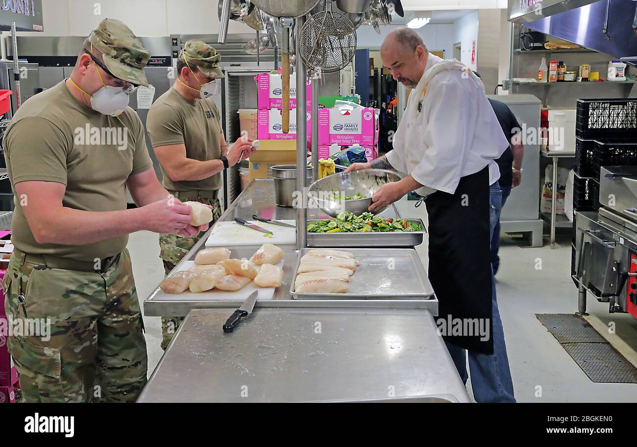 Alaska Army National Guard Soldiers Sgt. David Osmanson e il personale Sgt. Edward Jones, assegnato al Battaglione di reclutamento e conservazione AKARNG, lavora insieme ai dipendenti del Bean's Cafe, creando pranzi pre-confezionati in cucina al Bean's Cafe di Anchorage, Alaska, 8 aprile 2020. Questo cibo sarà distribuito a migliaia di locali Alaskans rifugio a Sullivan e Boeke arenas così come il programma di pranzo dopo la scuola Alaska. (STATI UNITI Foto della Guardia Nazionale dell'esercito di Sgt. Seth LaCount/rilasciato) Foto Stock