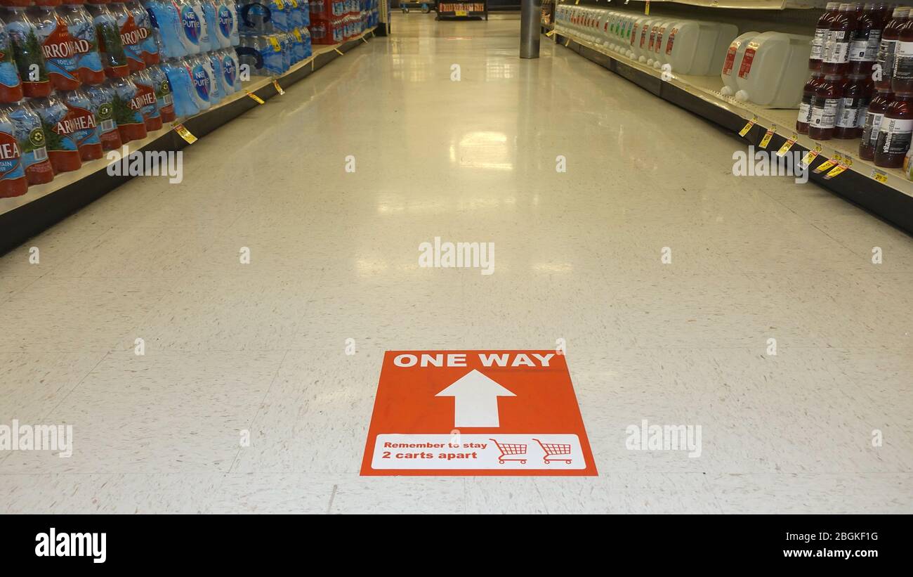 Un cartello sul pavimento di un negozio di alimentari ricorda agli acquirenti di mantenere la distanza per evitare la diffusione di virus. Foto Stock