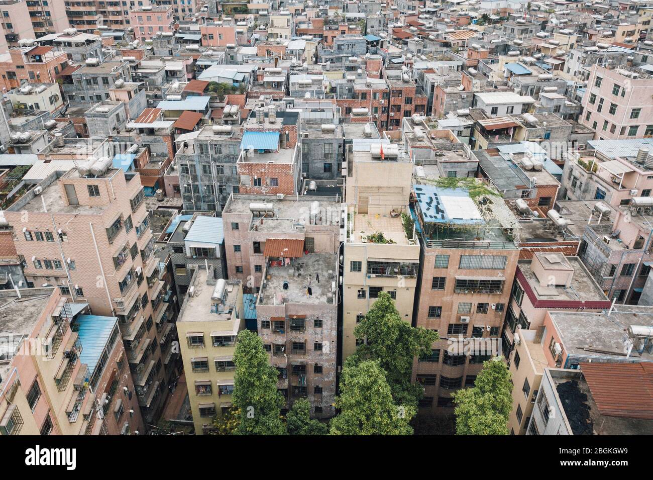 Una vista aerea di file di edifici residenti di varie altezze erigendo al centro della città, formando un mondo incompatibile con i cieli moderni circostanti Foto Stock