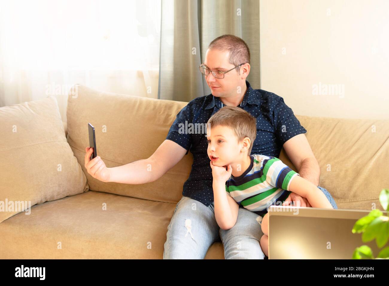 Padre e figlio comunicano online per telefono con parenti o amici. Comunicazione online, comunicazione remota. Foto Stock