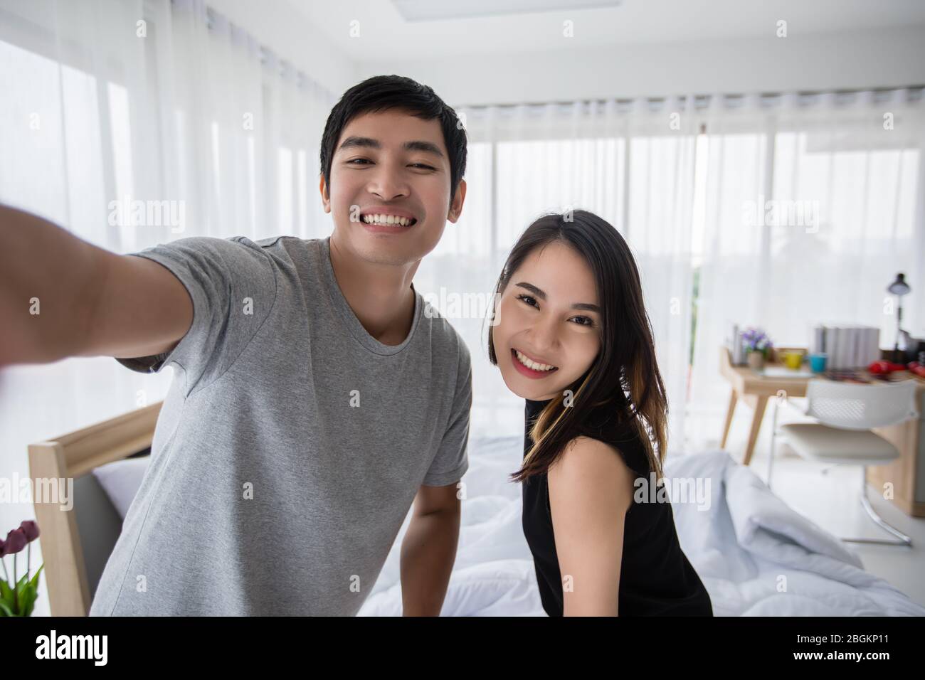 Gli amanti delle coppie asiatiche che si trovano sul loro telefono cellulare e selfie a letto a casa Foto Stock