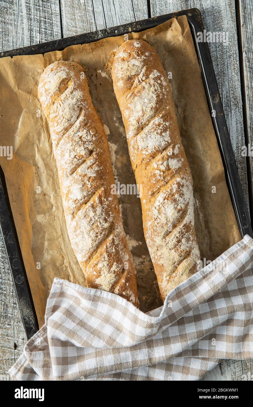 Baguette di pane di grano intero fresco su carta bagnata. Vista dall'alto. Foto Stock
