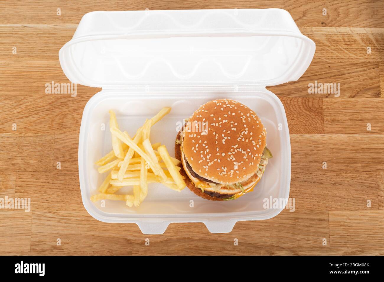 Delizioso hamburger e patatine fritte in una scatola di plastica bianca per la consegna in casa Foto Stock