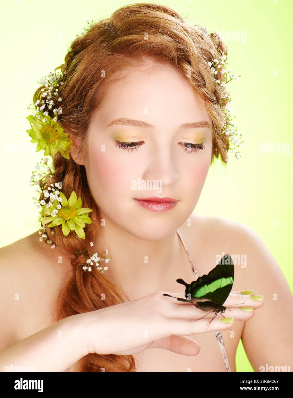 ritratto di bella ragazza giovane rossa sana con fiori nei suoi capelli tenendo farfalla a portata di mano Foto Stock