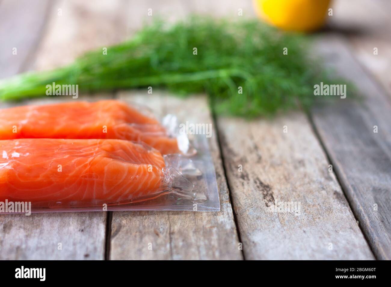 Filetti di pesce rosso o salmone su tavola di legno. Pesce fresco, limone e aneto per cucinare gli ingredienti. Omega-3. Messa a fuoco selettiva Foto Stock