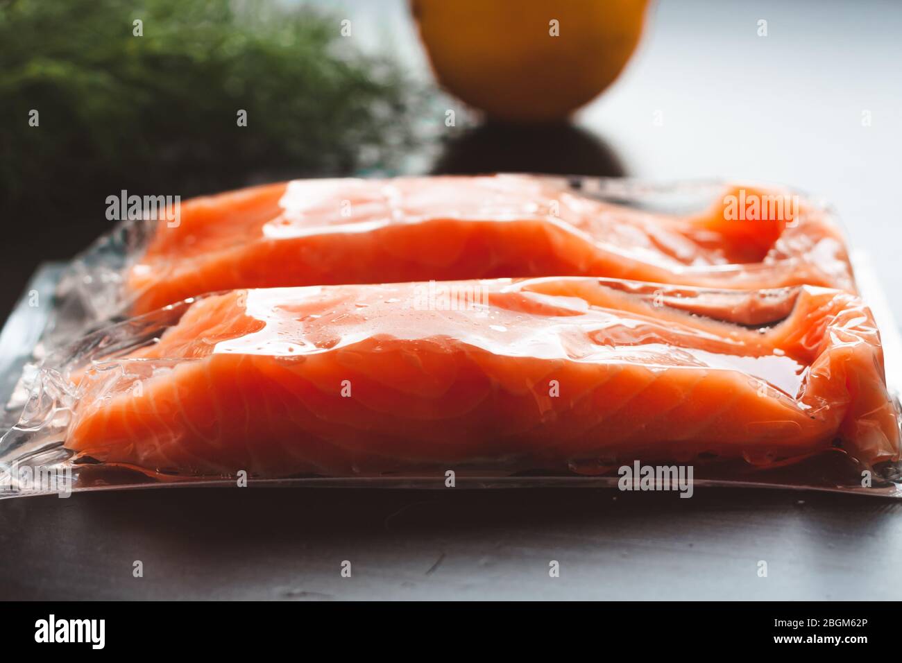 Filetti di pesce rosso o salmone in confezione sottovuoto su fondo nero. Concetto di alimentazione sana. Omega-3. Messa a fuoco selettiva. Foto Stock