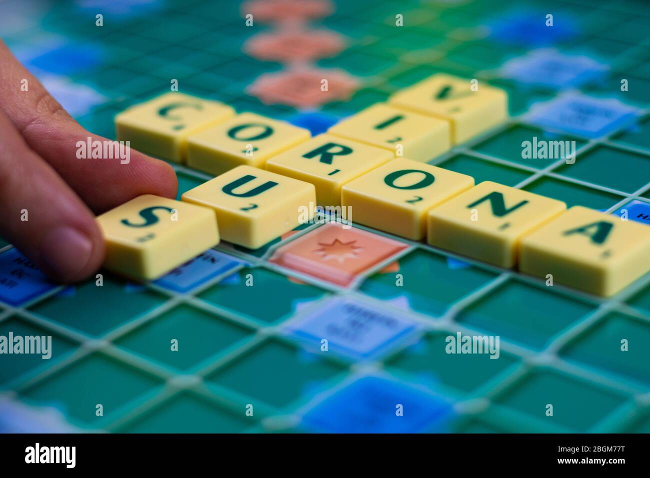 Dita femmina che tengono S per scrivere Corona Virus sul tabellone di gioco di parole nei giorni di quarantena di coronavirus Foto Stock