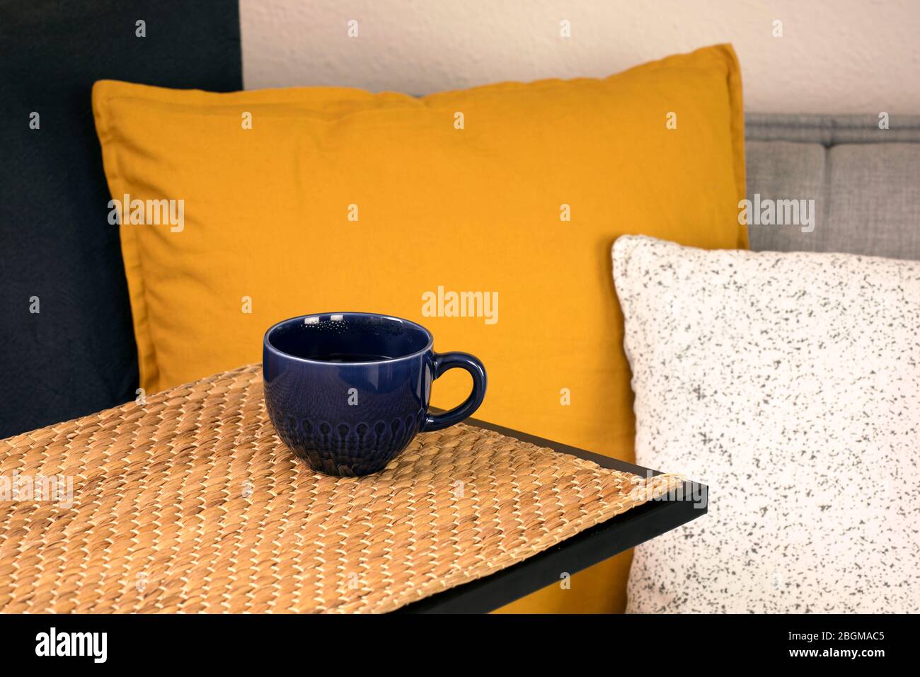 Tazza di caffè o tè sul tavolo con comodo divano con cuscini e cuscini. Tempo libero a casa. Ora del tè. Pausa caffè. Concetto di vita lenta. Foto Stock