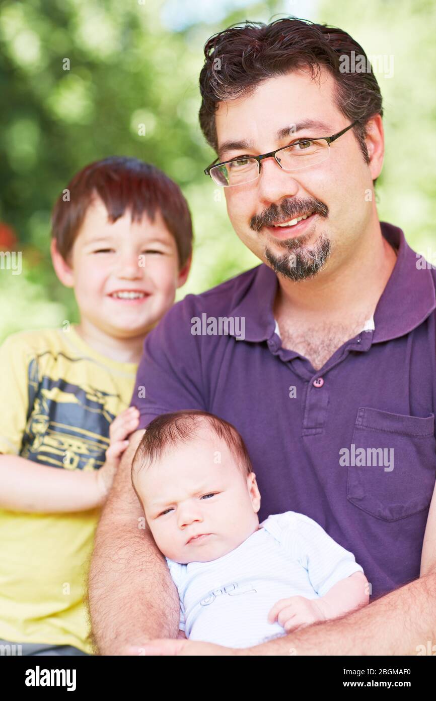 Lächelnder Vater mit seinen zwei Kindern im Garten Foto Stock