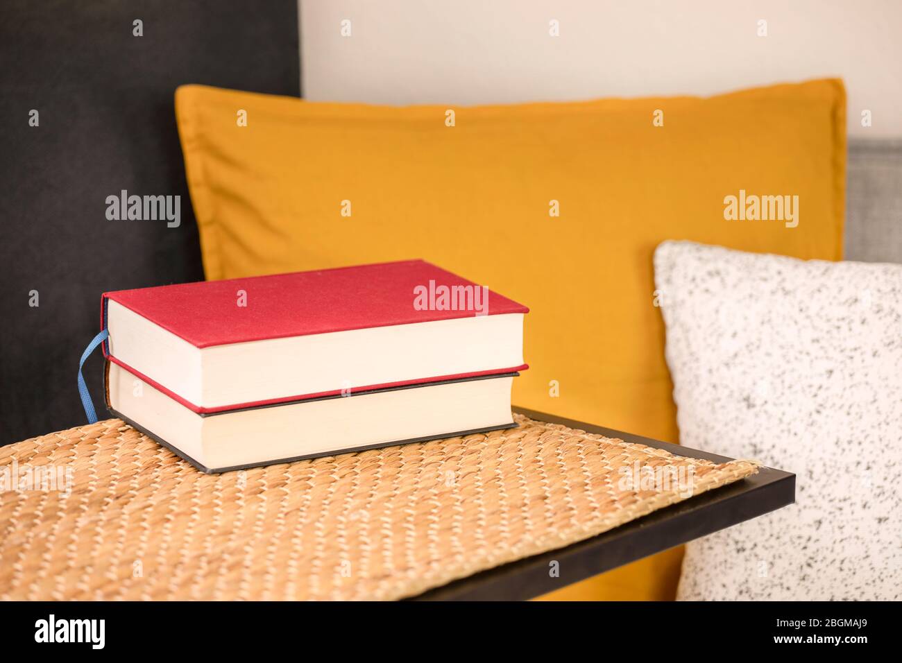 Alcuni libri sul tavolo con un comodo divano, cuscini e cuscini. Leggere libri, studiare a casa, imparare. Attività ricreative a casa. Foto Stock