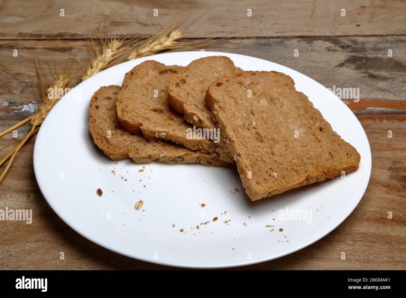 Quattro pane a grana multipla in un piatto di ceramica bianca su sfondo di legno Foto Stock