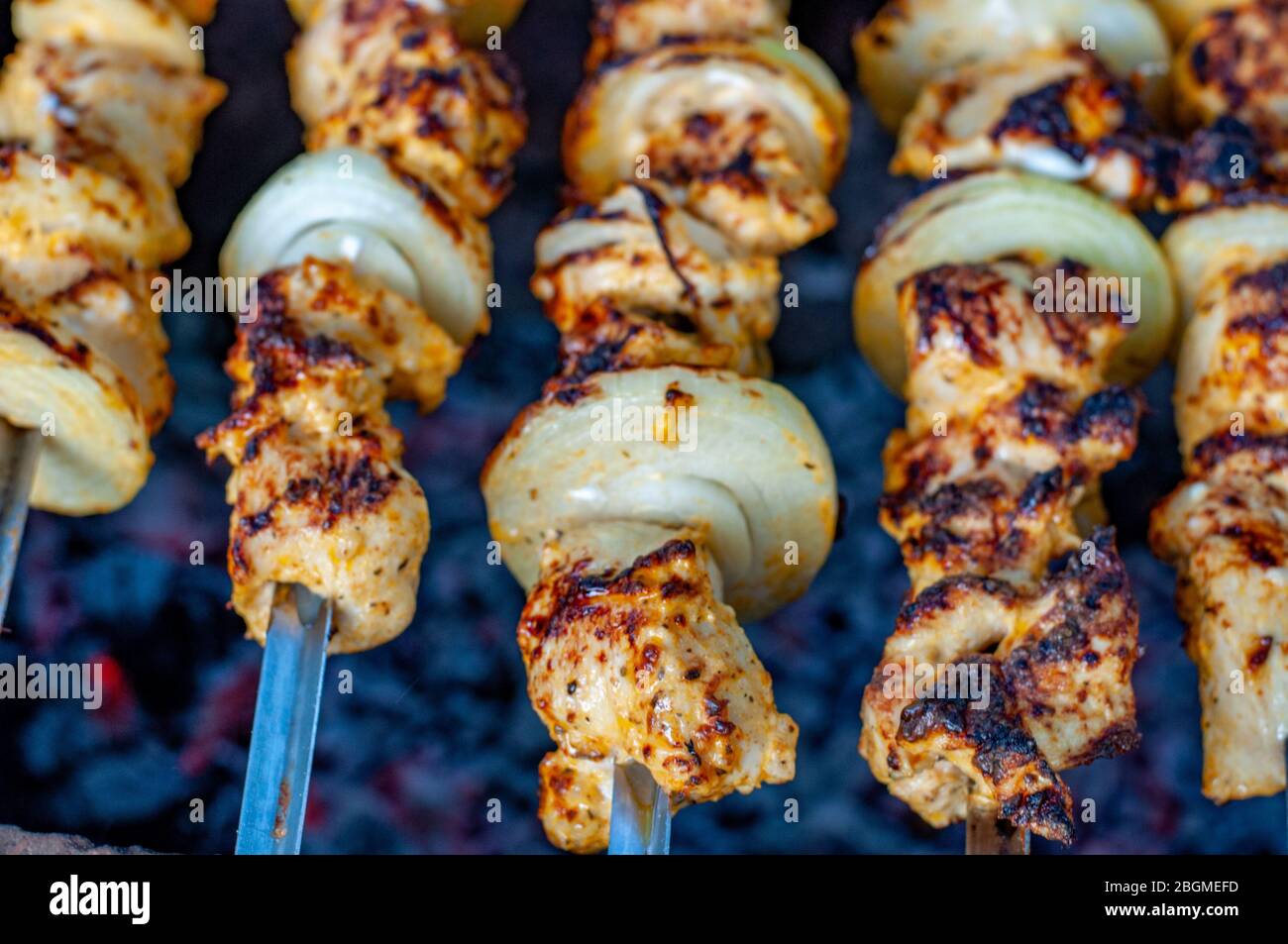 Primo piano di barbecue caldo pic-nic cibo. Deliziosi kabob di pollo arrostiti con cipolle bianche fresche. Focalizzazione morbida su spiedini di carne di pollo alla griglia. Foto Stock