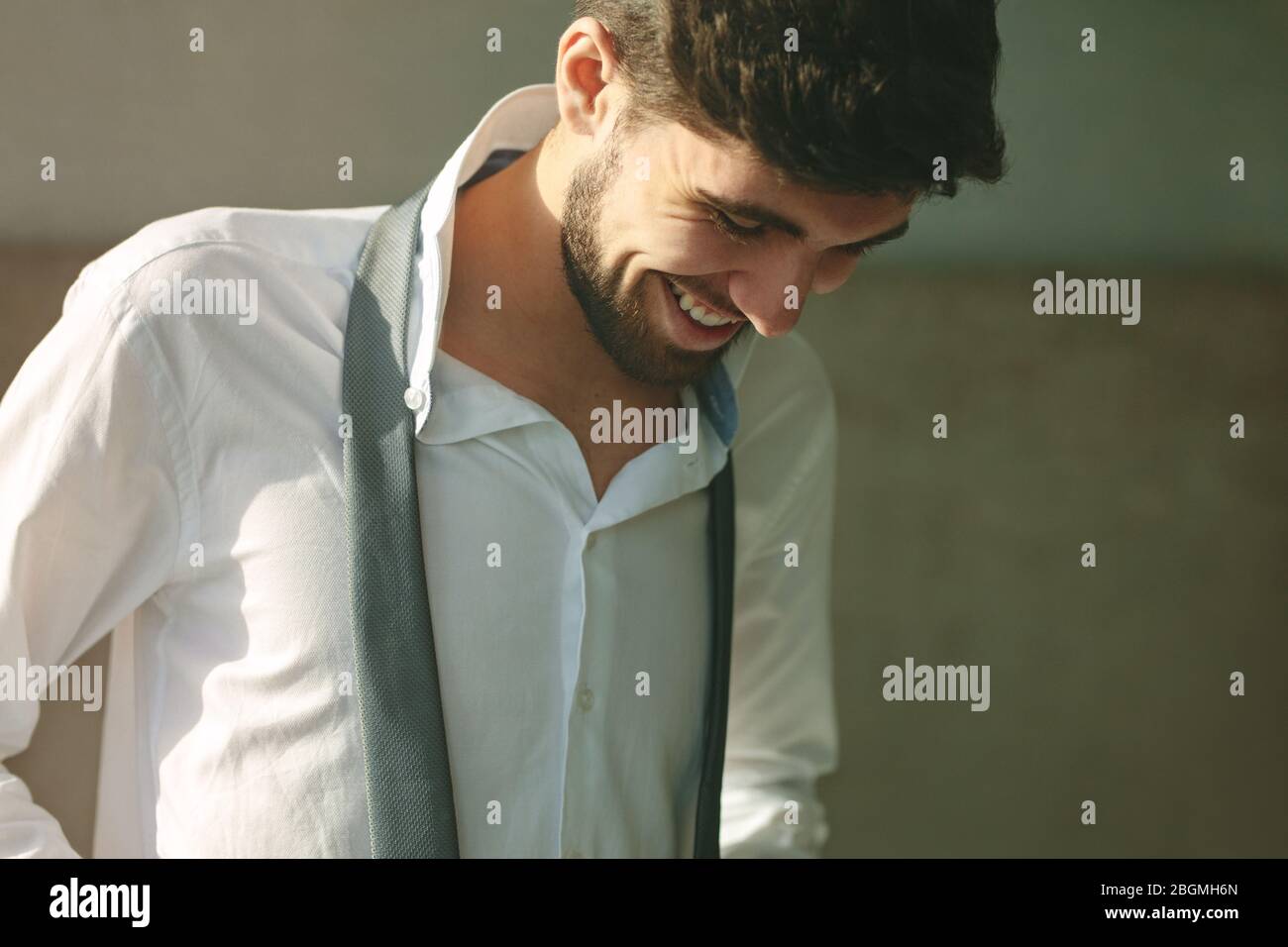 Uomo sorridente che si veste di mattina. uomo d'affari che si prepara per l'ufficio, indossa camicia e cravatta a casa. Foto Stock