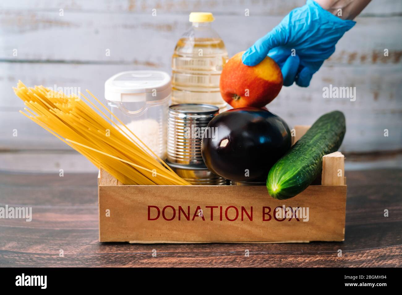 Forniture alimentari. Crisi alimentare scorta di scatola per il periodo di isolamento di quarantena di coronavirus in legno sfondo. Diversi alimenti in lattine di alluminio, riso, pasta, olio Foto Stock