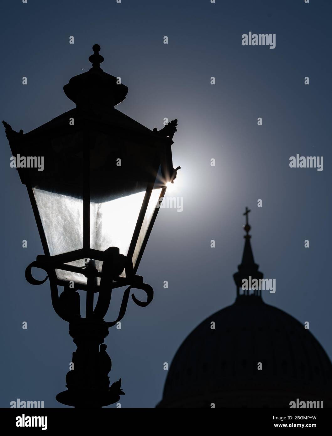 Potsdam, Germania. 22 aprile 2020. Il sole è dietro la replica di una storica lampada da strada di fronte alla sagoma della cupola della chiesa di San Nicola. Credit: Soeren Stache/dpa-Zentralbild/ZB/dpa/Alamy Live News Foto Stock