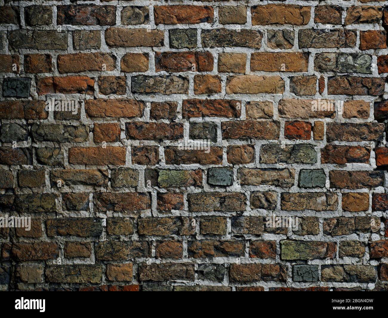 Frammento di un muro medievale del castello fatto di mattoni vari nella forma e colore, tonalità scure Foto Stock