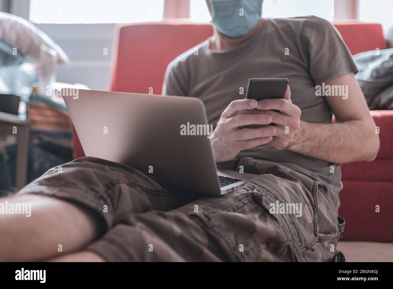 Lavorare da casa - telelavoro durante covid-19 coronavirus focolaio, uomo che utilizza il computer portatile e cellulare Foto Stock