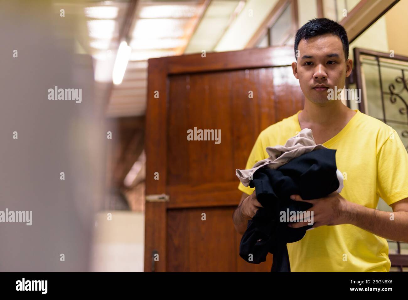 Ritratto di giovane uomo asiatico che lava vestiti a casa Foto Stock