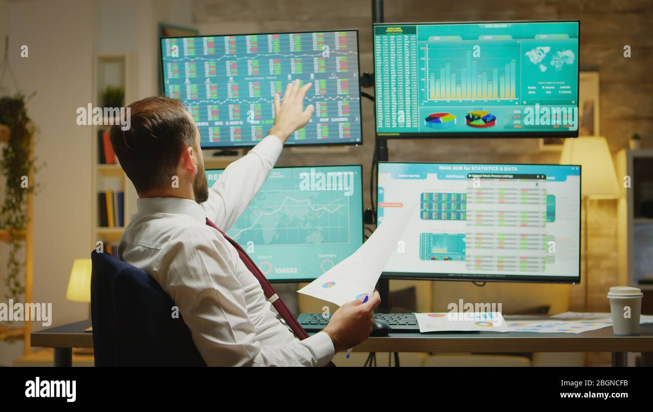 Barbuto commerciante di borsa che prende un sorso di caffè mentre legge un grafico circa il declino finanziario. Foto Stock