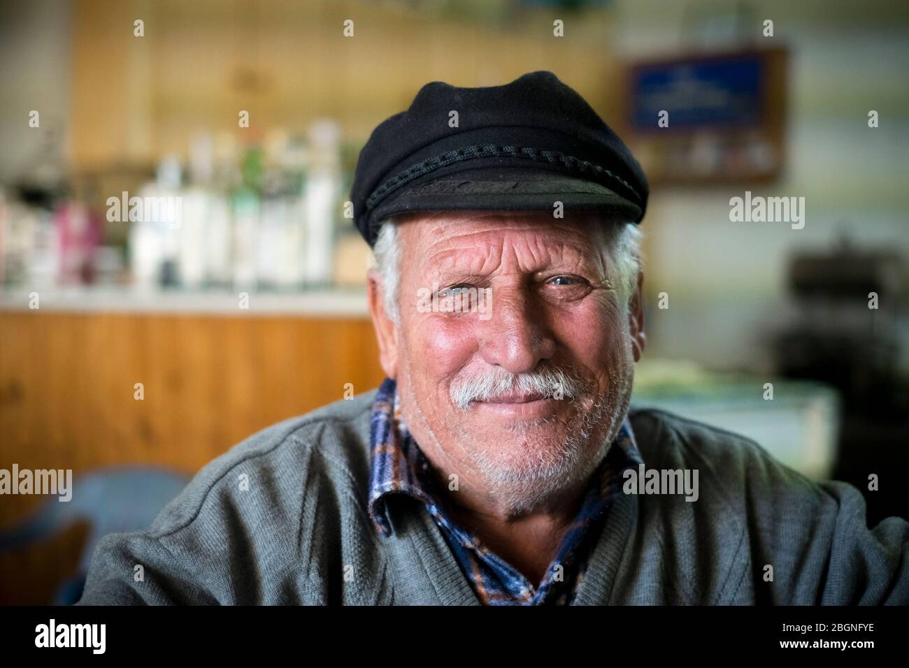 Uomo locale anziano che indossa un cappello piatto in un bar nel villaggio di Dhrousha, Akamas Heights, Cipro Foto Stock