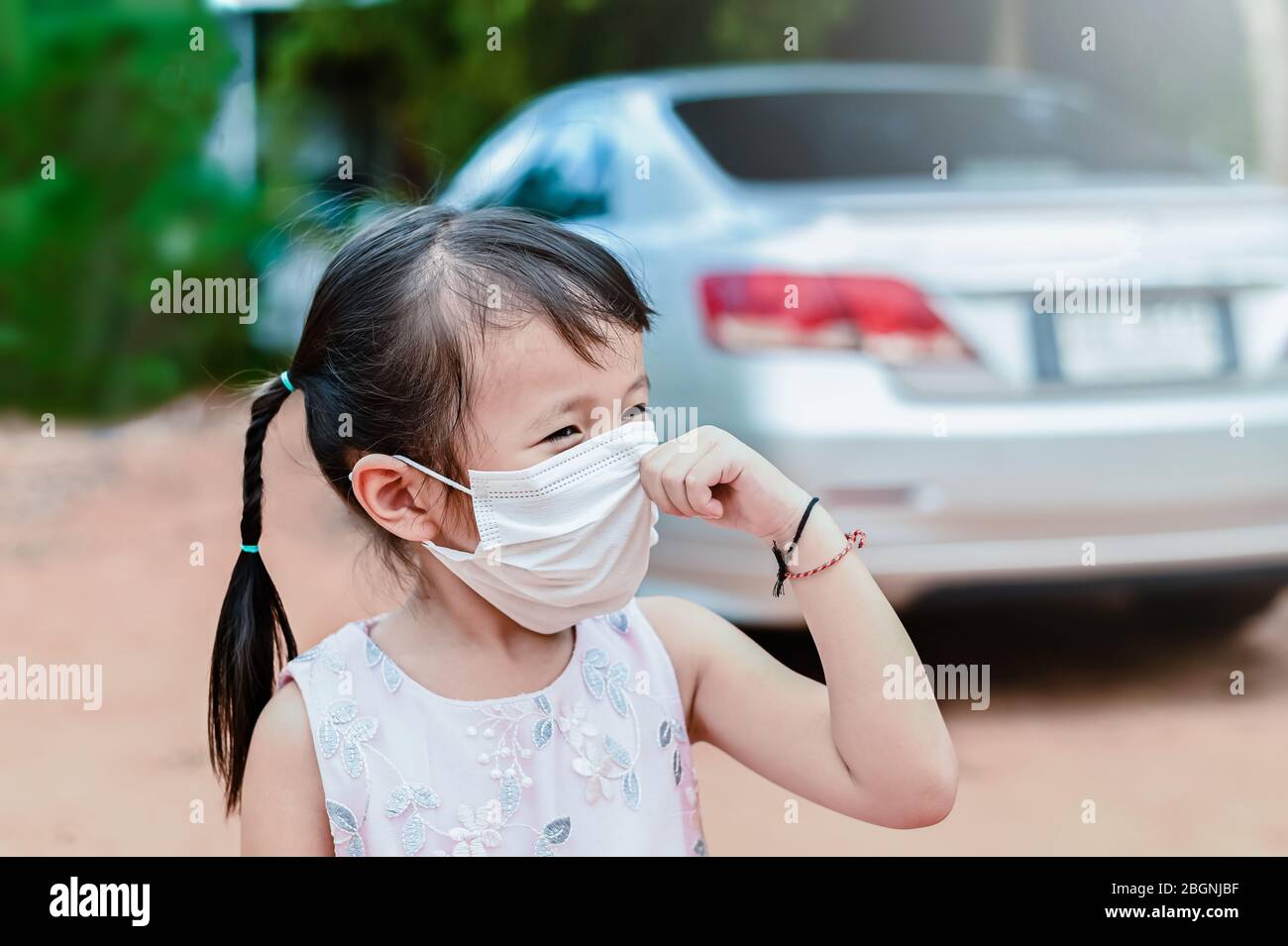 Bambina ha maschera medica viso proteggere se stessa da Coronavirus COVID-19, mano stop segno quando il bambino lasciare la casa,, bambino con una maschera sul naso Foto Stock