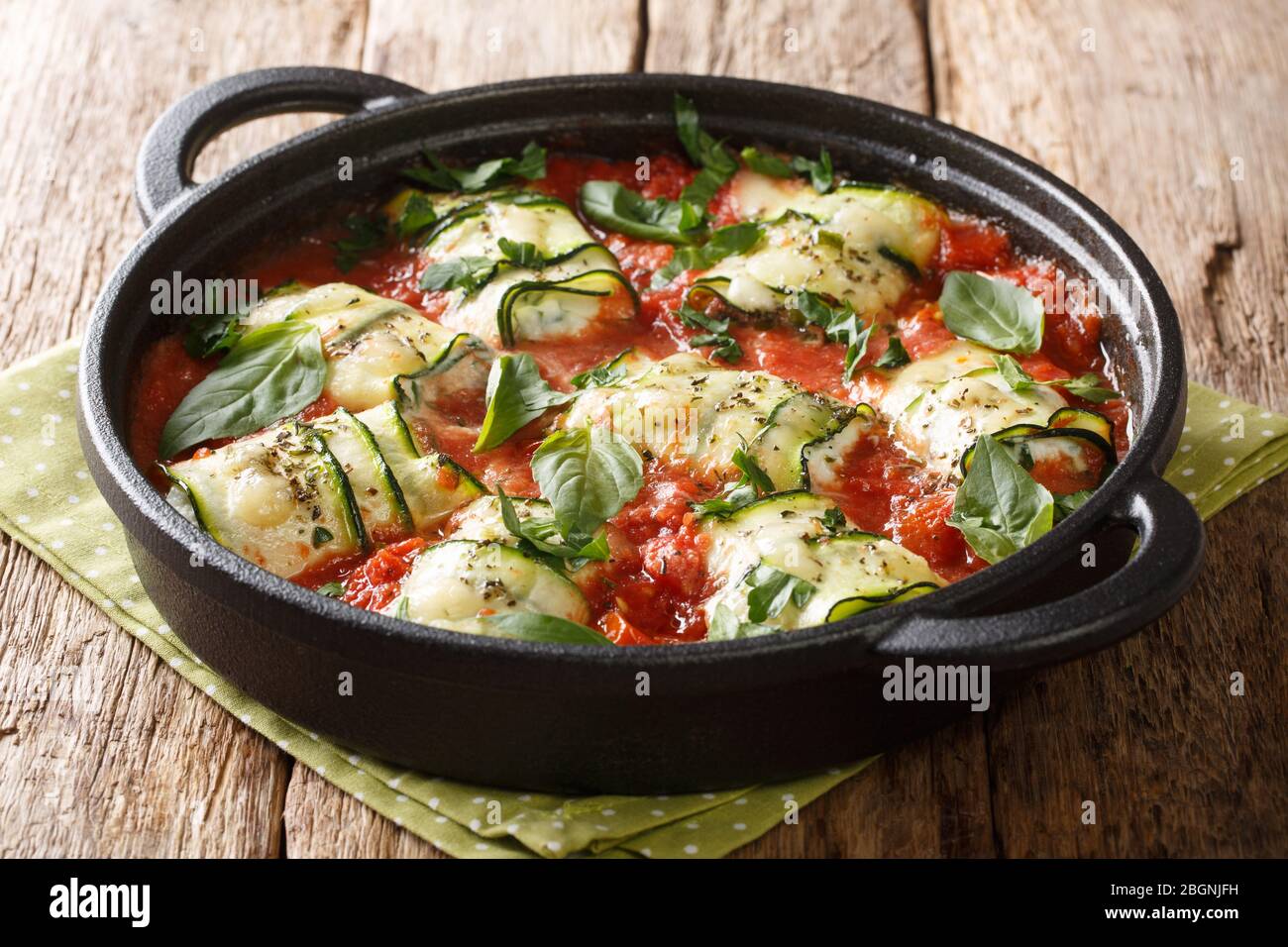 Involtini di zucchine con ricotta e basilico in salsa di pomodoro in una padella sul tavolo. Orizzontale Foto Stock