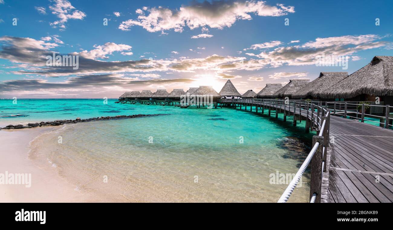 Vista panoramica panoramica panoramica di lussuosi bungalow sull'acqua sulla spiaggia e sulla laguna durante il tramonto a Moorea, Polinesia francese. Foto Stock