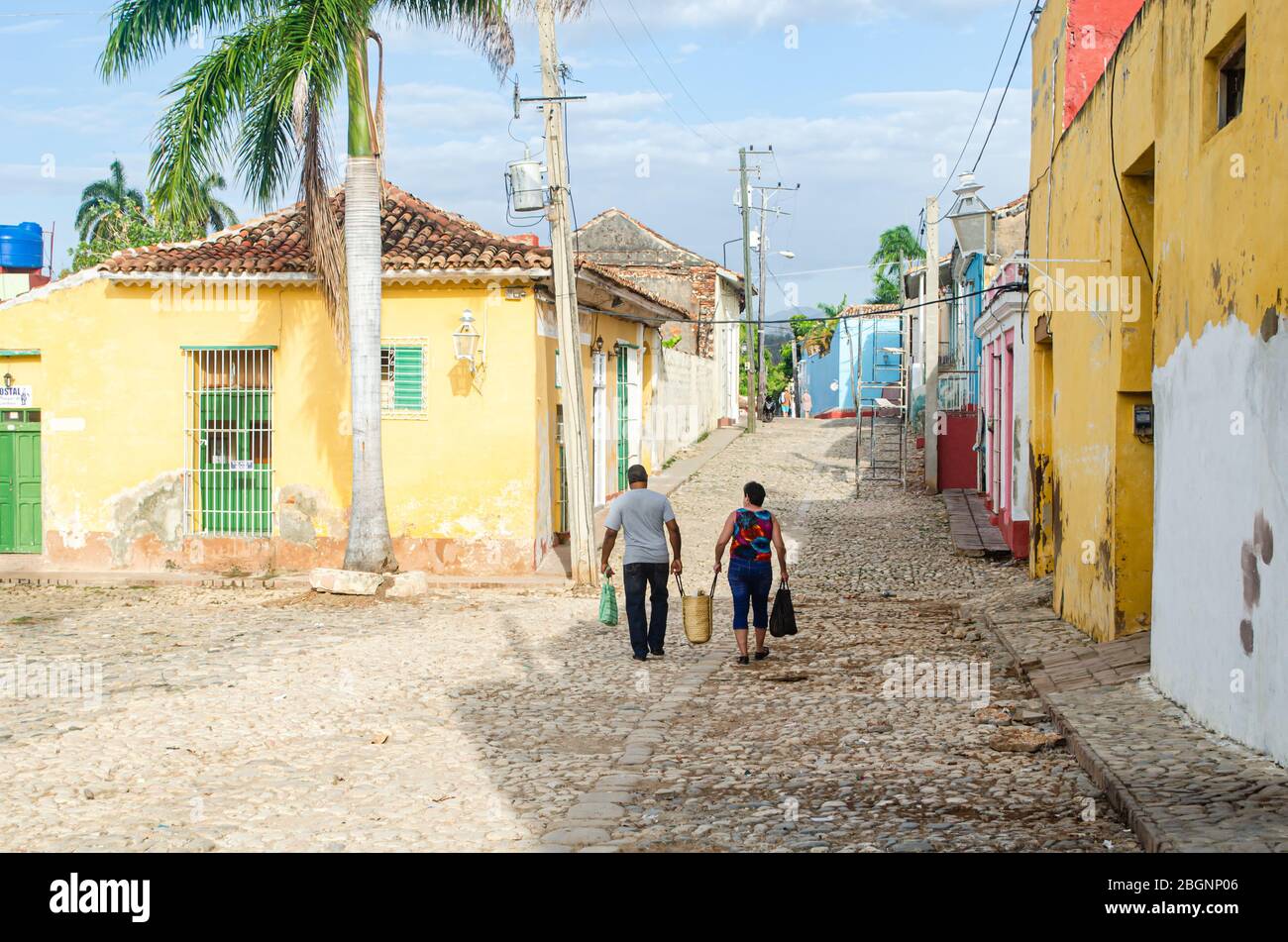 Scena mattutina per le strade di Trinidad a Cuba. Una coppia sta camminando con i cestini tradizionali dello shopping della paglia Foto Stock