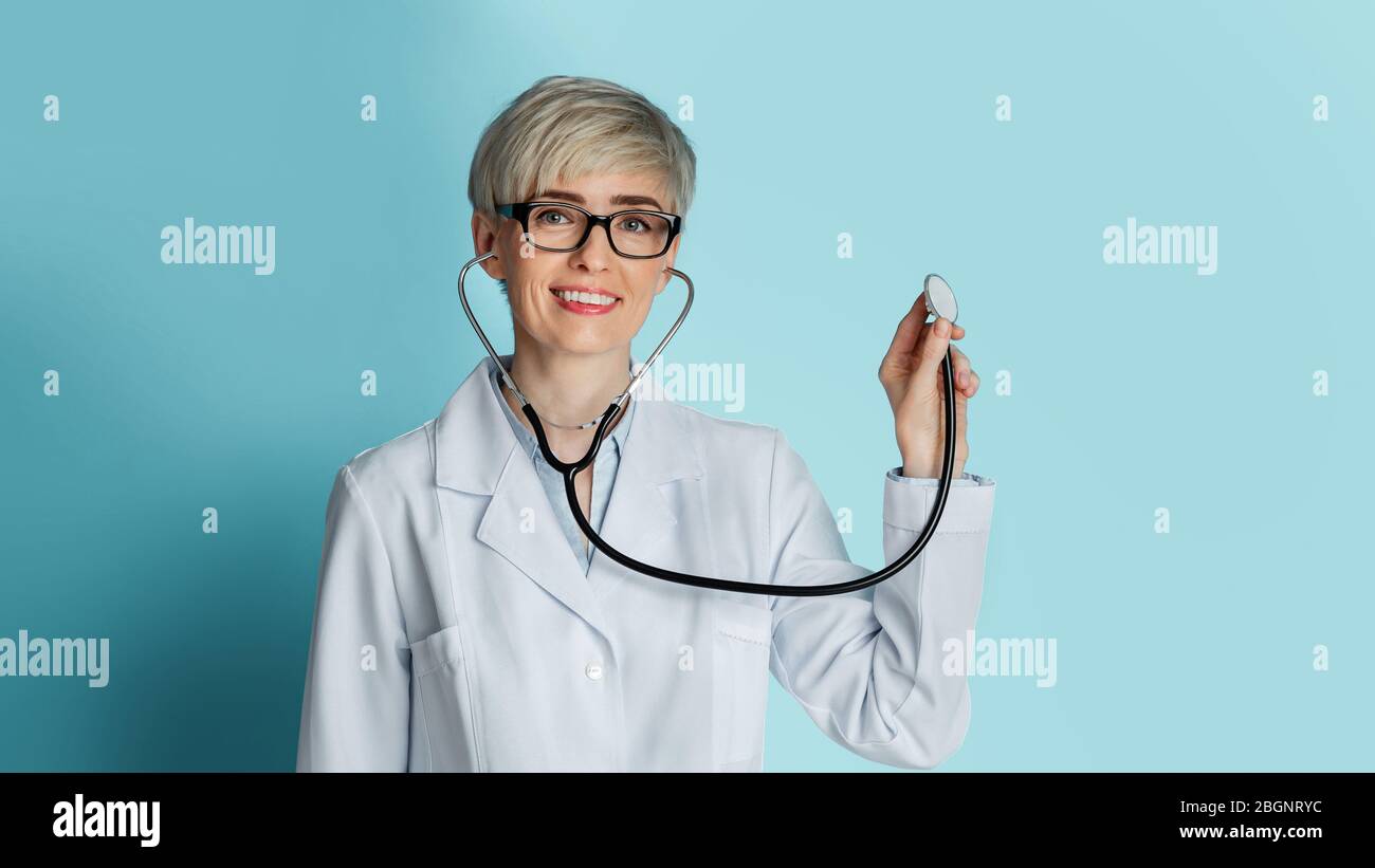 Bel medico con occhiali ascolta attraverso stetoscopio Foto Stock