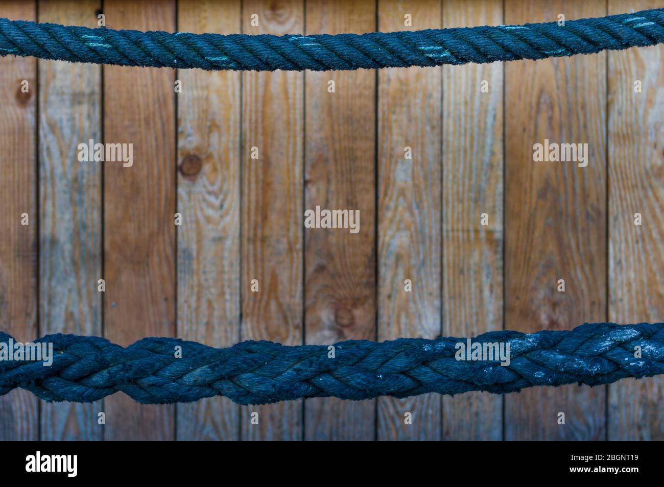 corda blu sottile come corrimano nella parte superiore e corda spessa nella parte inferiore terza. Parete di legno sullo sfondo con nitidezza selettiva Foto Stock