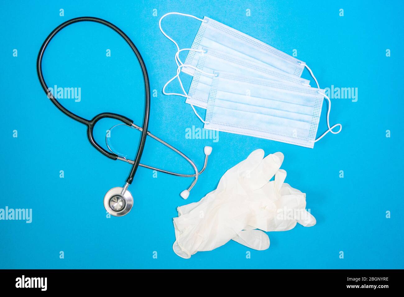 primo piano di stetoscopio, maschera facciale e guanto chirurgico su sfondo blu Foto Stock