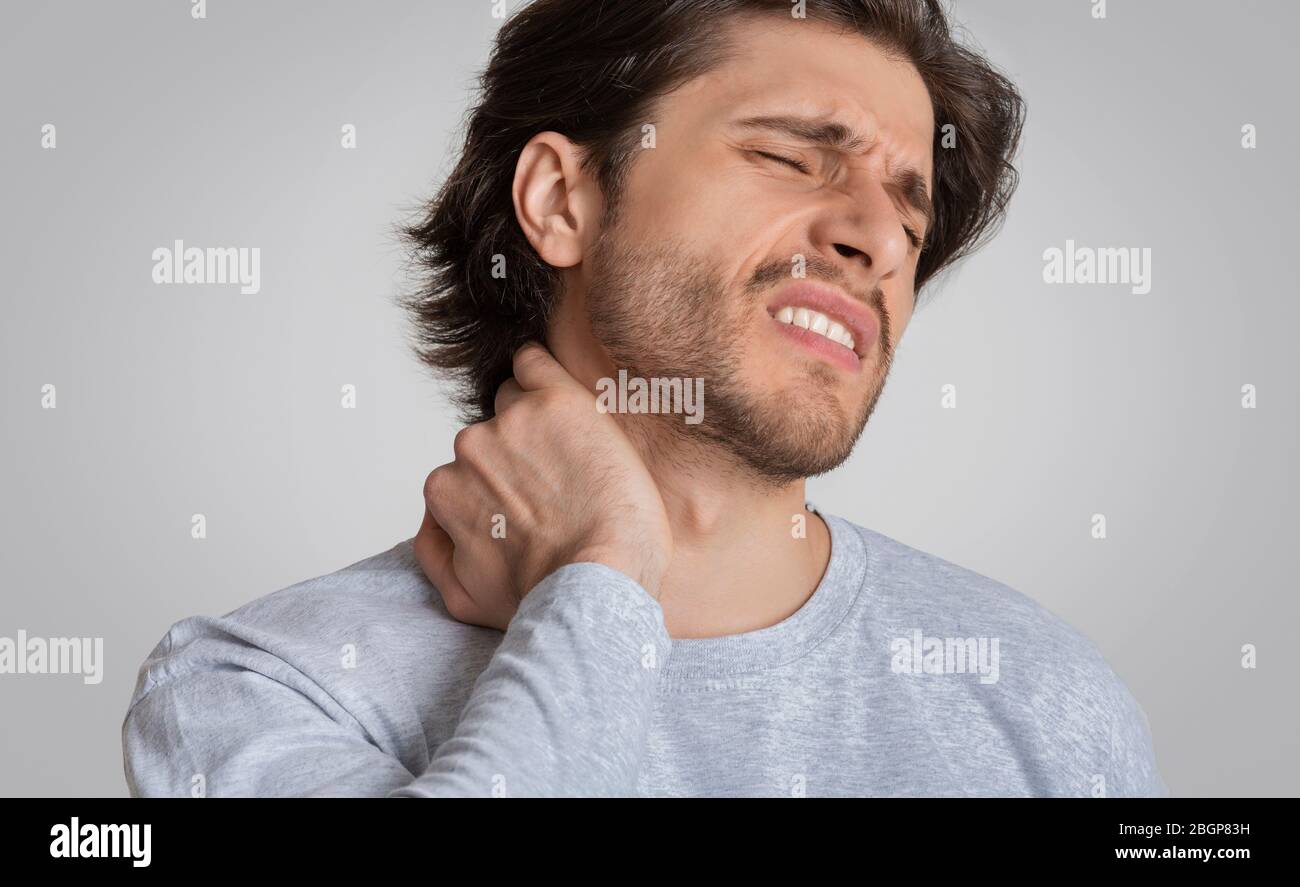 L'uomo con espressione dolorosa gli sfrega il collo Foto Stock