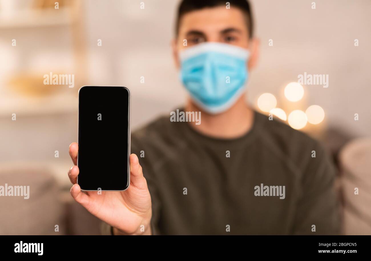 Uomo che indossa una maschera chirurgica con lo smartphone Foto Stock