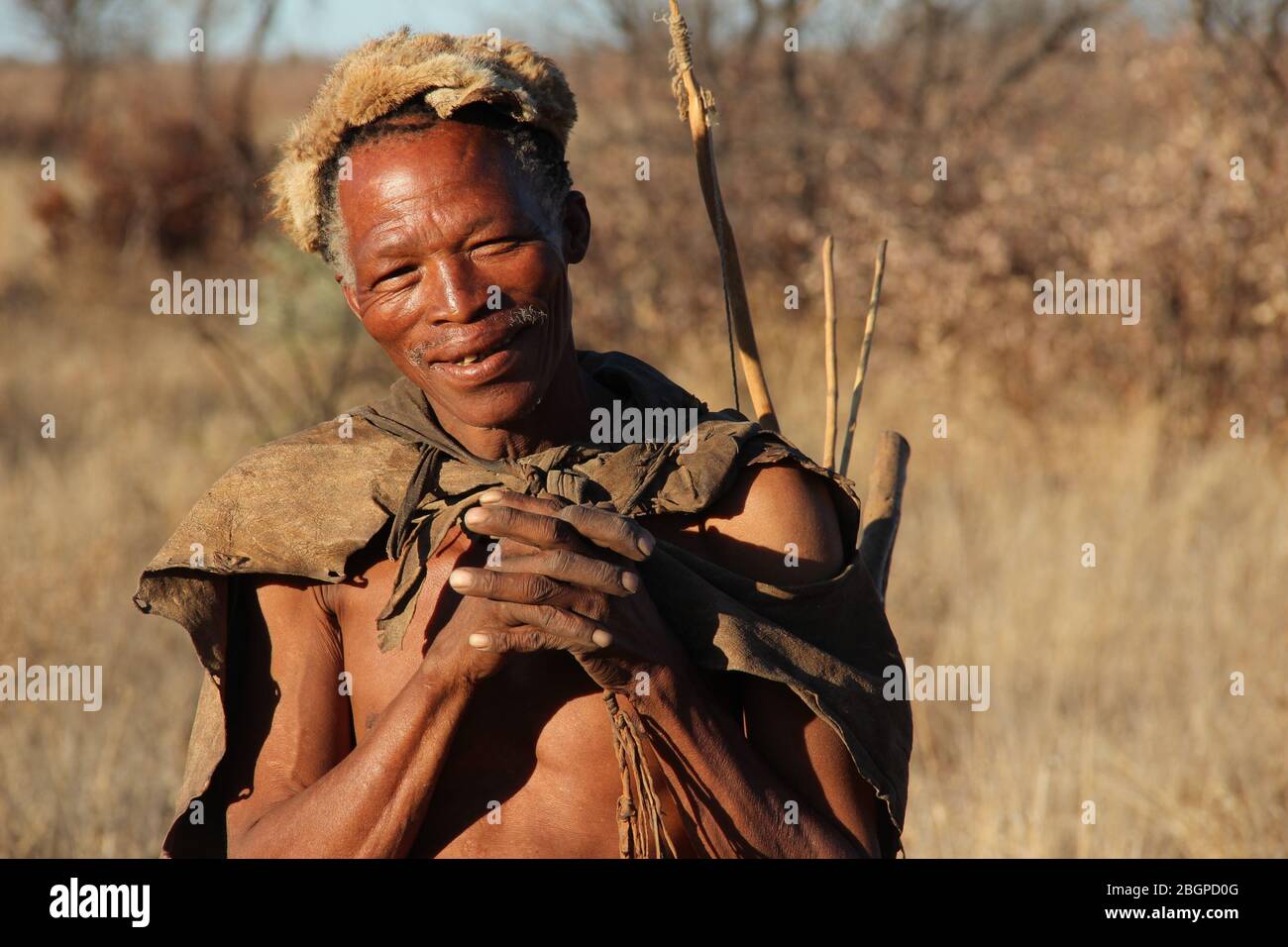 Un uomo di cespuglio di Kalahari sorride per una foto nel paesaggio desertico del Botswana Foto Stock