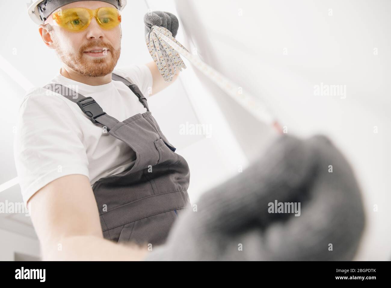 Elettricista che installa il nastro di montaggio striscia LED illuminazione decorativa Foto Stock