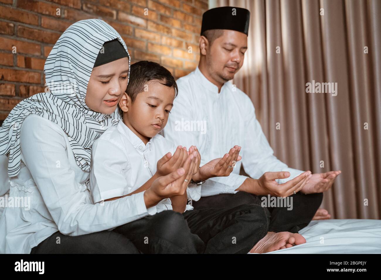 la famiglia musulmana prega sul letto prima di dormire Foto Stock