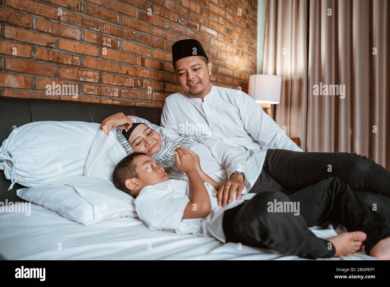 la famiglia musulmana prega sul letto prima di dormire Foto Stock
