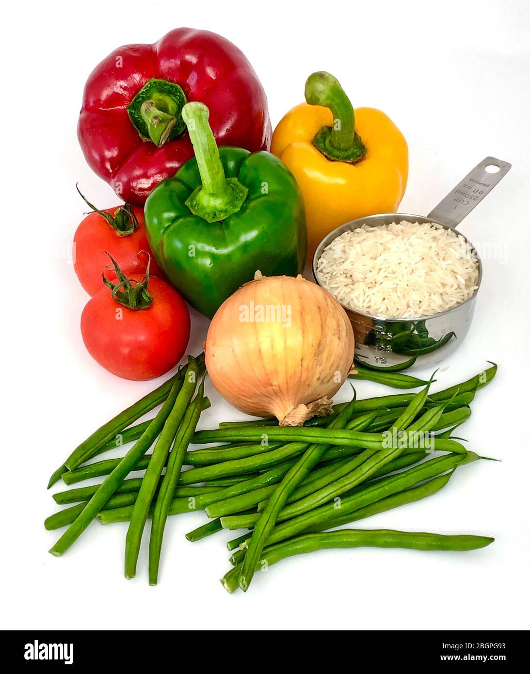 Una selezione di cibi sani su un bancone da cucina bianco che attende di essere preparato, include riso, fagioli verdi, cipolla, pomodoro e peperoni. Foto Stock