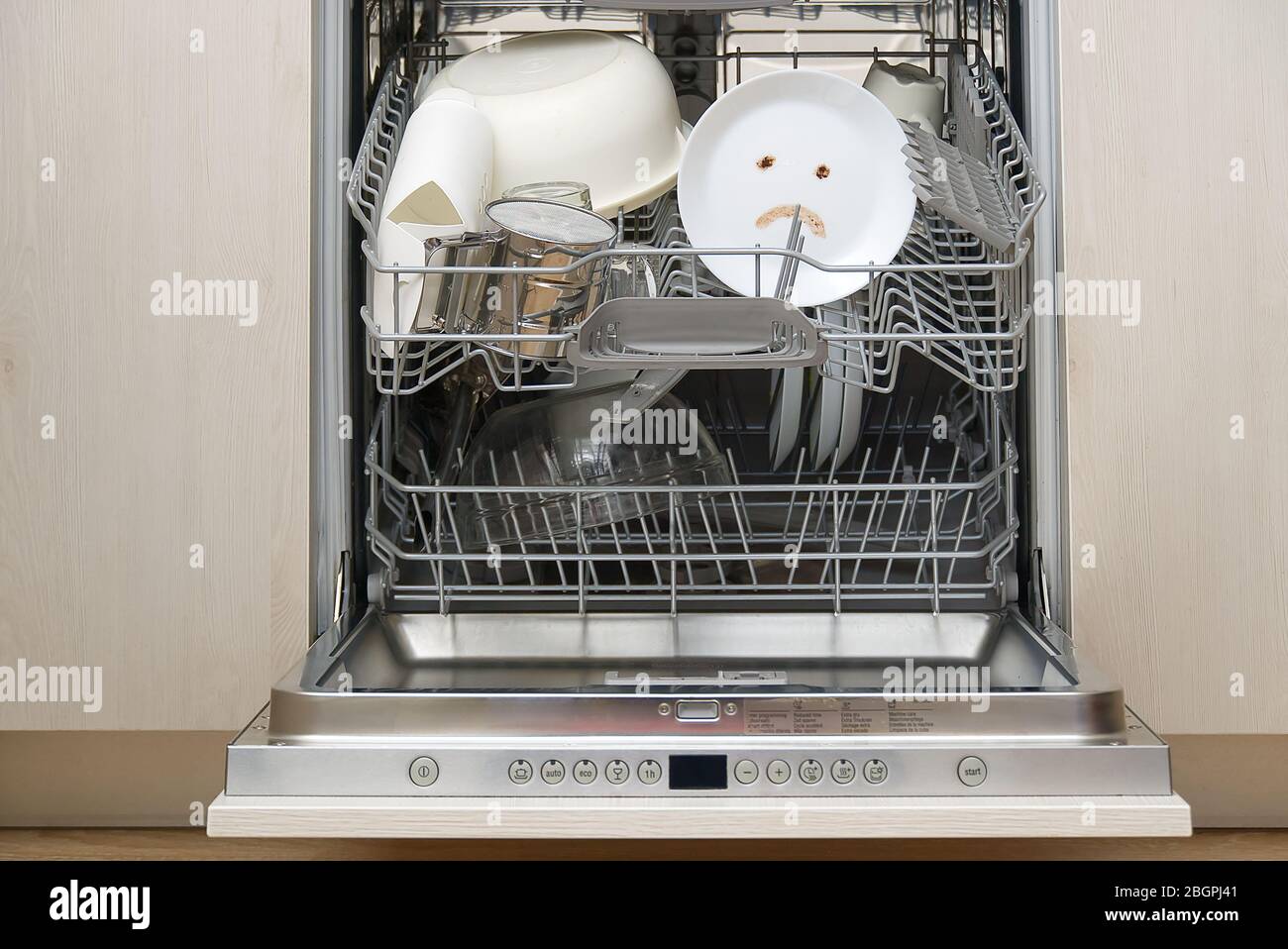 Piatti lavati male in lavastoviglie. Lavastoviglie integrata con piastre bianche davanti a vew e triste emozione su piastra. Macchina lavastoviglie rotta concetto Foto Stock