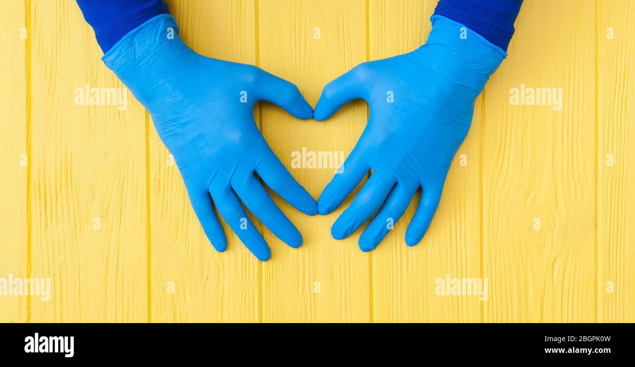 Guanti blu in nitrile. Mani di medica nei guanti blu in lattice sul banner giallo tavolo in legno Foto Stock