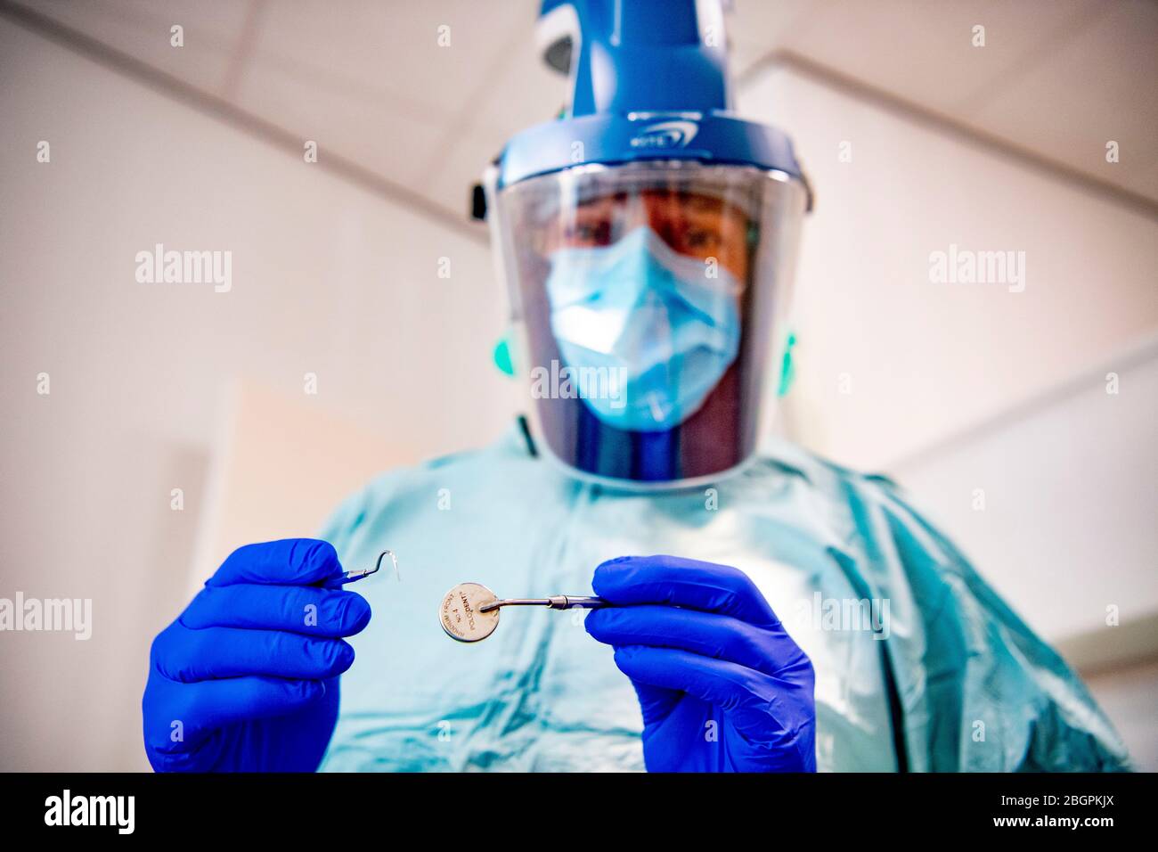 Un dentista che indossa un equipaggiamento protettivo.i dentisti tornano al lavoro dopo che le restrizioni dopo la quarantena sono state sollevate e devono operare con dispositivi di protezione contro la diffusione del virus corona. Foto Stock