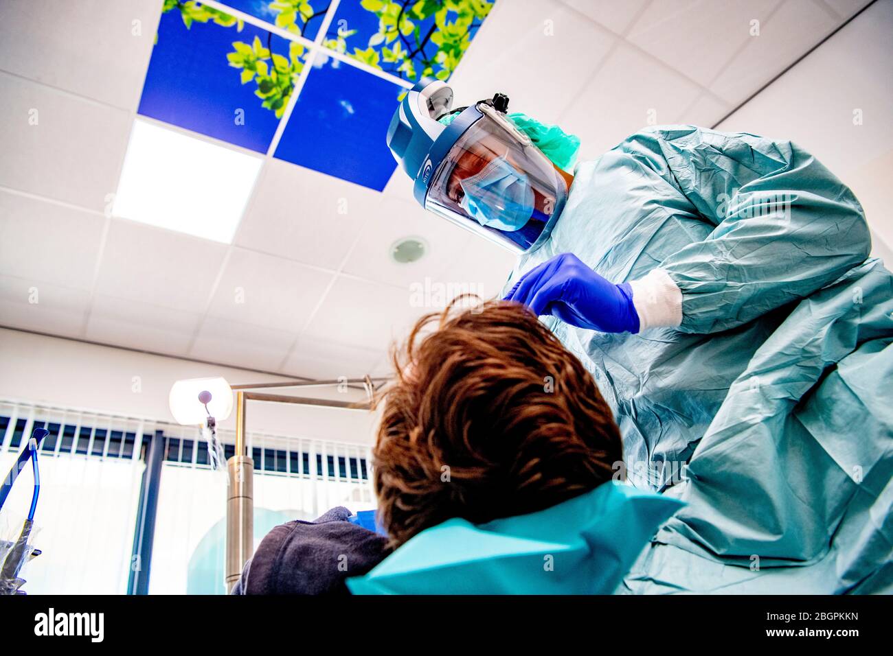 Un dentista che opera con dispositivi di protezione.i dentisti tornano al lavoro dopo che le restrizioni dopo la quarantena sono state sollevate e devono operare con dispositivi di protezione contro la diffusione del virus corona. Foto Stock