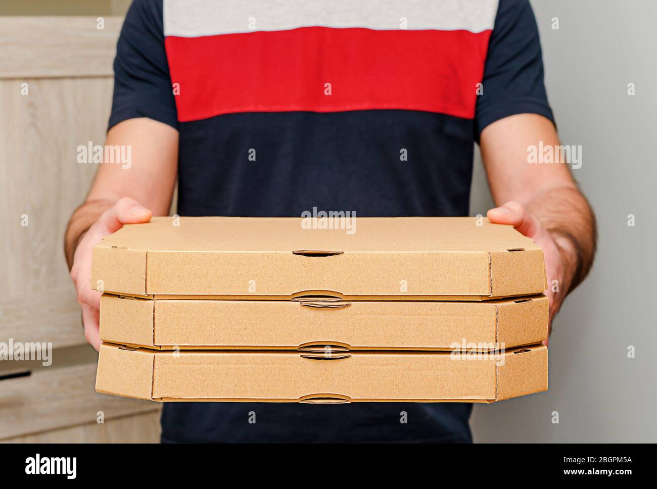 Mani maschili che tengono scatole di cartone per pizza. Servizio di consegna di cibo. Foto Stock