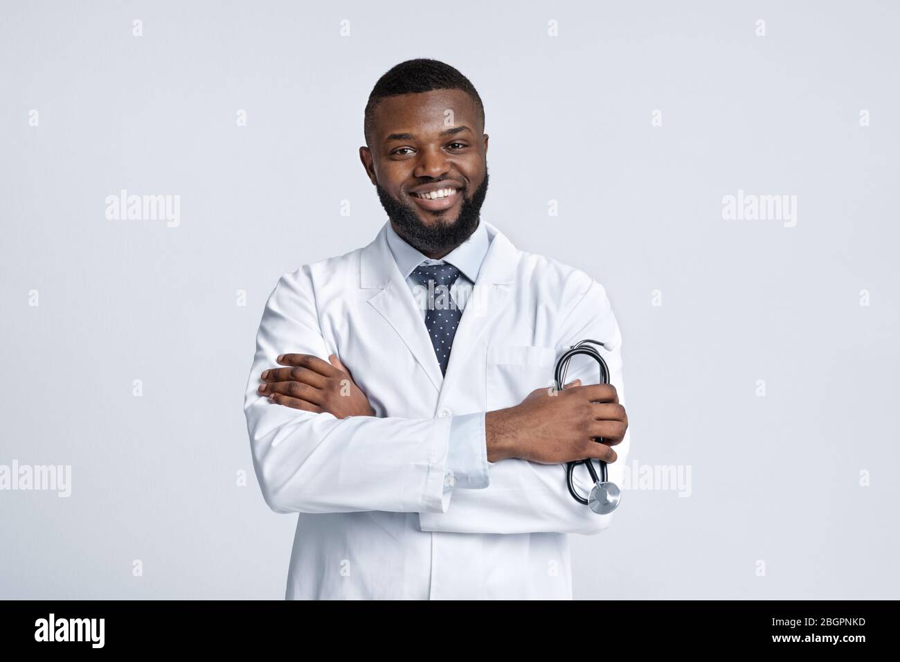 Sicuro medico africano sorridente su sfondo bianco studio Foto Stock