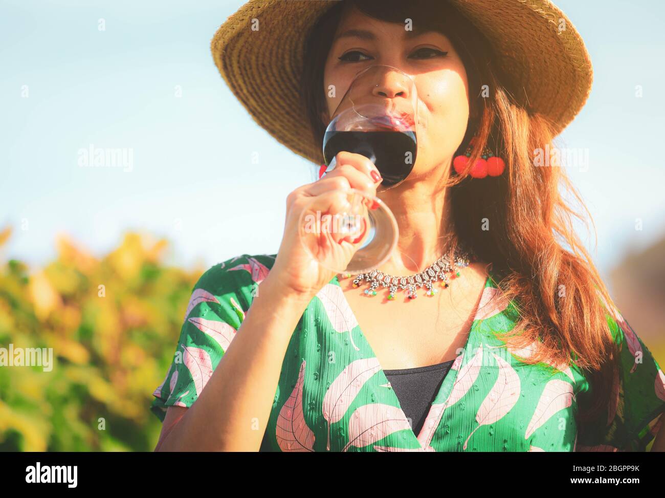 Felice donna asiatica bere vino rosso bicchiere, concetto di celebrazione Foto Stock